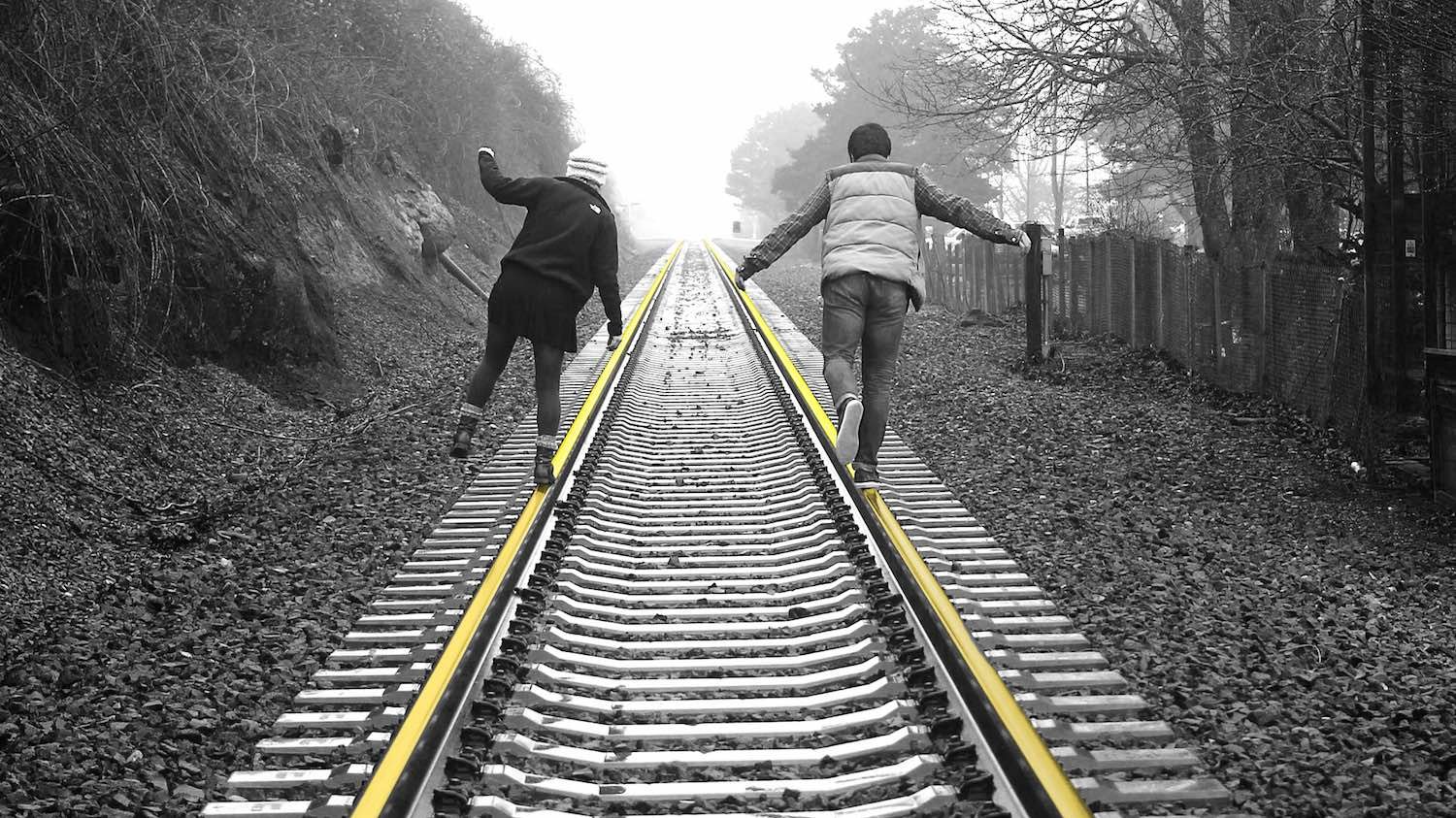Deux adolescents marchant en équilibre sur des rails de chemin de fer
